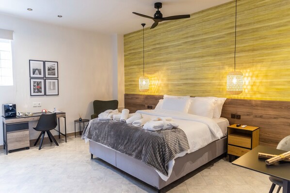 Habitación de hotel moderna con cama, escritorio, silla y ventilador de techo instalado en la pared.