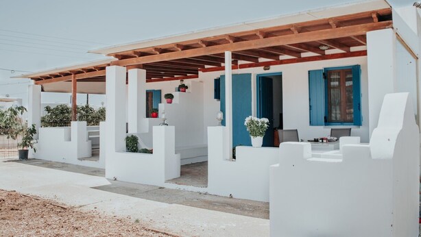A white building with blue shutters, a wooden pergola, and potted plants. - Moonlight Kastraki beach house (Kastraki)