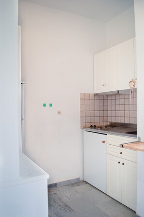 A small kitchen with white cabinets, a tiled backsplash, and a stove.