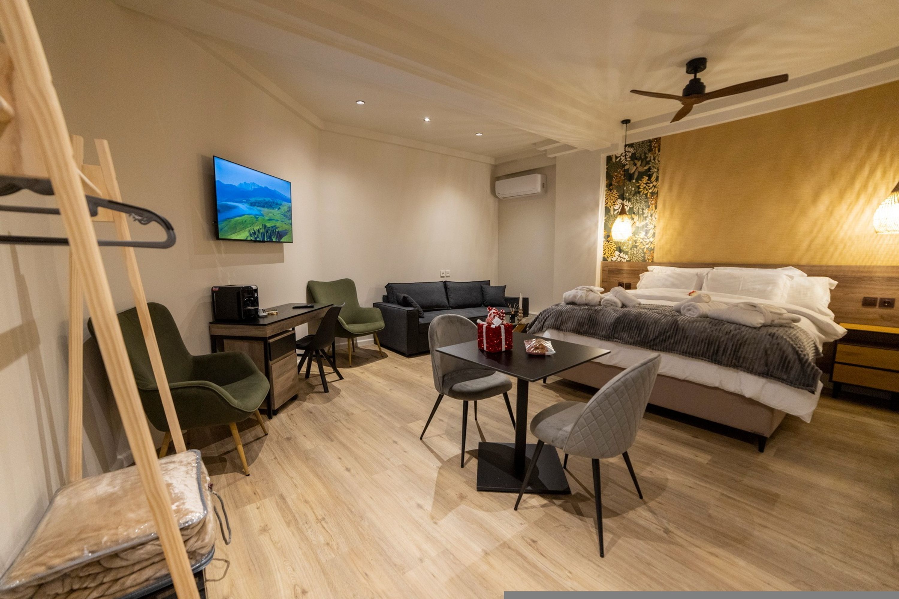 Une chambre d’hôtel moderne équipée d’un lit, d’un bureau avec une chaise, d’un canapé et d’un téléviseur fixé au mur.
