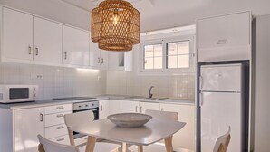 Une cuisine moderne avec des meubles blancs, un four à micro-ondes, une cuisinière, un évier et un réfrigérateur.