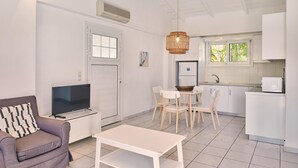 Ett modernt vardagsrum med en soffa, en tv och en matplats med stolar och ett bord.