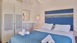 Un dormitorio con cama, armario blanco y cabecera azul.