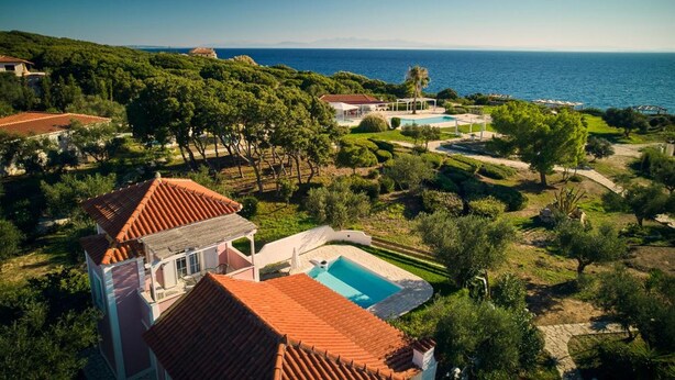 Eine Villa mit Swimmingpool, umgeben von üppiger Vegetation und Meerblick.