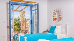 Un dormitorio con dos camas, una pared de piedra y vistas al verdor.