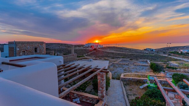 Terraza en la azotea con vista al atardecer, edificios de piedra y cielo despejado.