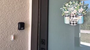 A door with a 'welcome' sign and a light switch. - Chic New Build Duplex /King Suite & Cover Lanai (Punta Gorda)