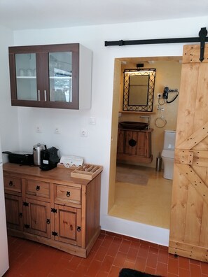 A compact room with a wooden cabinet, a mirror, and a sliding door leading to a bathroom. - Stephany's Skyline Studio (Paros)
