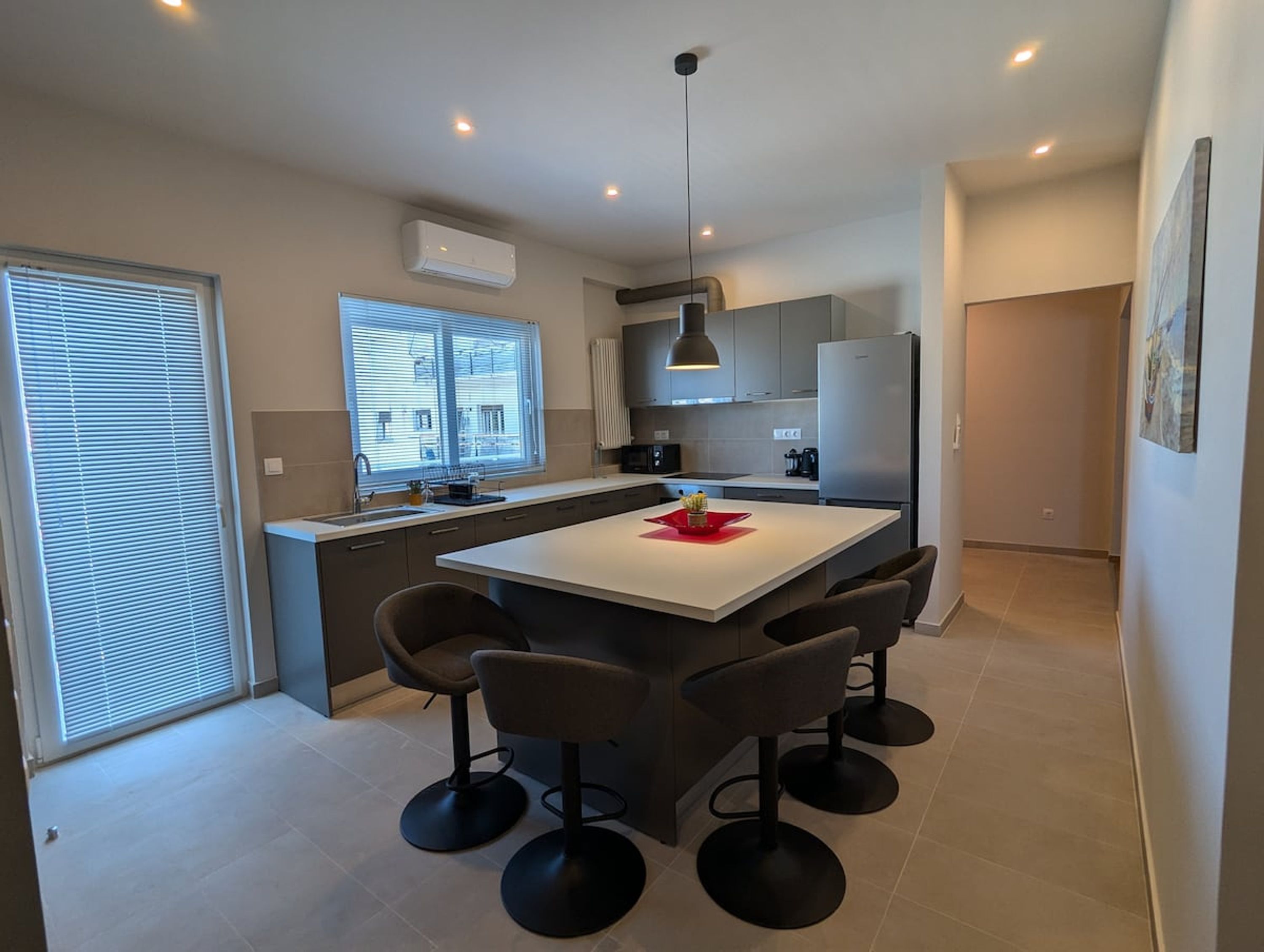 Een moderne keuken met een centraal eiland, barstoelen en een koelkast.