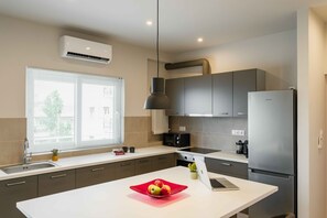 Eine moderne Küche mit einer zentralen Kochinsel, einem eingebauten Backofen und einem Edelstahlkühlschrank.