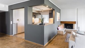 A modern living room with a grey accent wall, a fireplace, and a seating area with a sofa and a coffee table. - Spacious and sunlit seaside flat (Alimos)