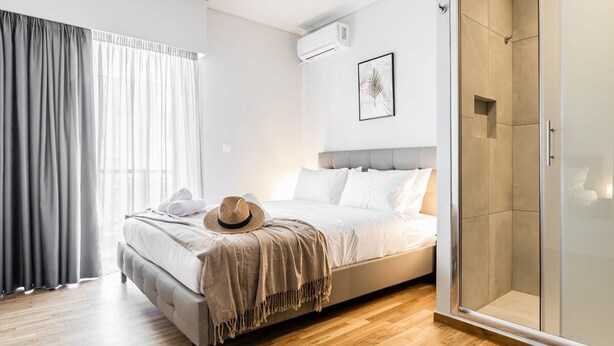 A modern bedroom with a bed, a hat, a framed picture, and a walk-in closet. - Spacious and sunlit seaside flat (Alimos)