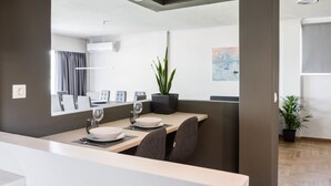 A modern dining area with a long table, chairs, and a potted plant. - Spacious and sunlit seaside flat (Alimos)