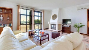 A living room with a sofa, a coffee table, a fireplace, a television, and a bookshelf. - Villa Mar in Albufeira (Albufeira)