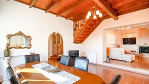 A spacious dining area with a wooden table and chairs, a large mirror, and a staircase leading to an upper level. - Loris Residence in Ionian Islands (Ionian Islands)