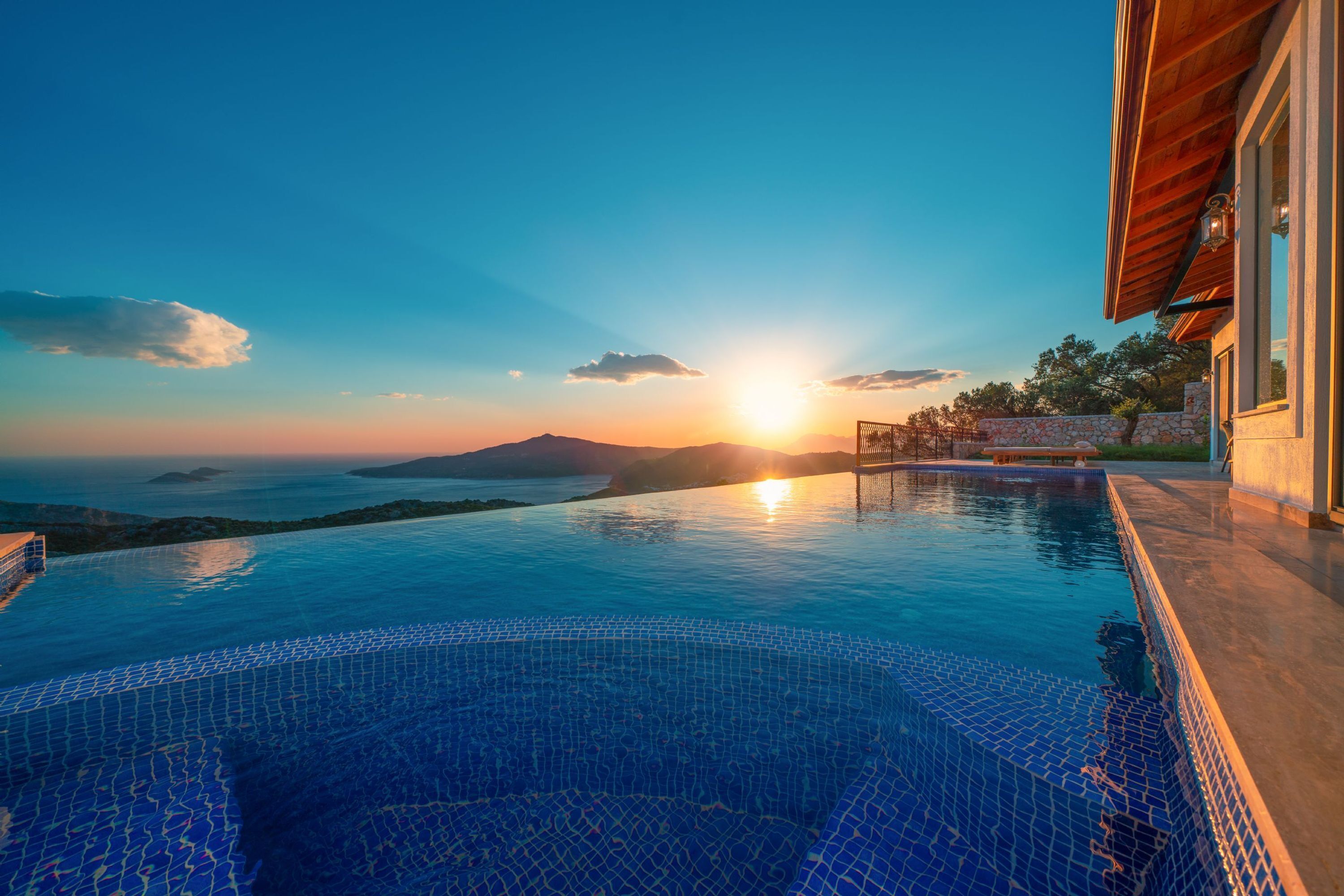 Une piscine à débordement offrant une vue imprenable sur le coucher de soleil, la mer et les montagnes.
