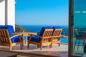 A terrace with wooden furniture and a view of the sea. - Akasya Ena in Kalkan Belediyesi (Kalkan Belediyesi)