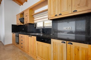 A kitchen with wooden cabinets, a black countertop, and a built-in oven. - Akasya Ena in Kalkan Belediyesi (Kalkan Belediyesi)