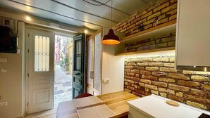 Cocina compacta con mesa de madera, estufa integrada y pared decorativa de ladrillo.