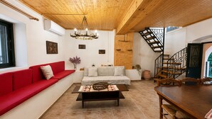A modern living room with a red sofa, a wooden coffee table, a staircase, and a dining area. - Kansoneta-Traditional Mansion in Gastouri Village (Achilleio)