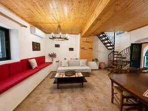 Ein modernes Wohnzimmer mit einem roten Sofa, einem Holztisch, einer Treppe und einem Essbereich.