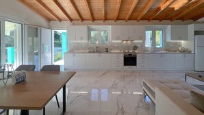 Une cuisine moderne avec des meubles blancs, un plan de travail en marbre et un plafond en bois.