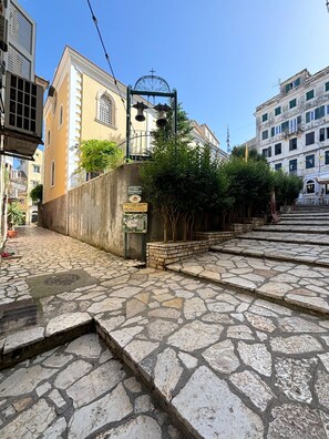 Eine Kopfsteinpflasterstraße mit einer Steintreppe, die zu einem Gebäude mit einem Glockenturm hinaufführt.