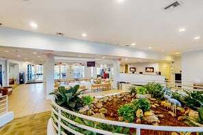 A spacious lobby with a central water feature, seating areas, and a reception desk. - Condo near orlando (Davenport)