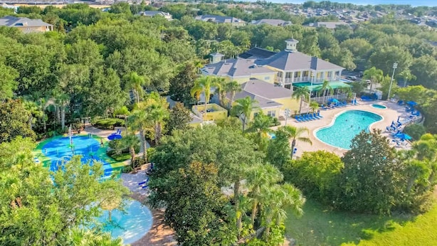 Zona residencial con una piscina grande, varias casas y abundante vegetación.