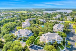 A residential area with multiple two-story houses, a swimming pool, and a large body of water in the background. - Condo near orlando (Davenport)