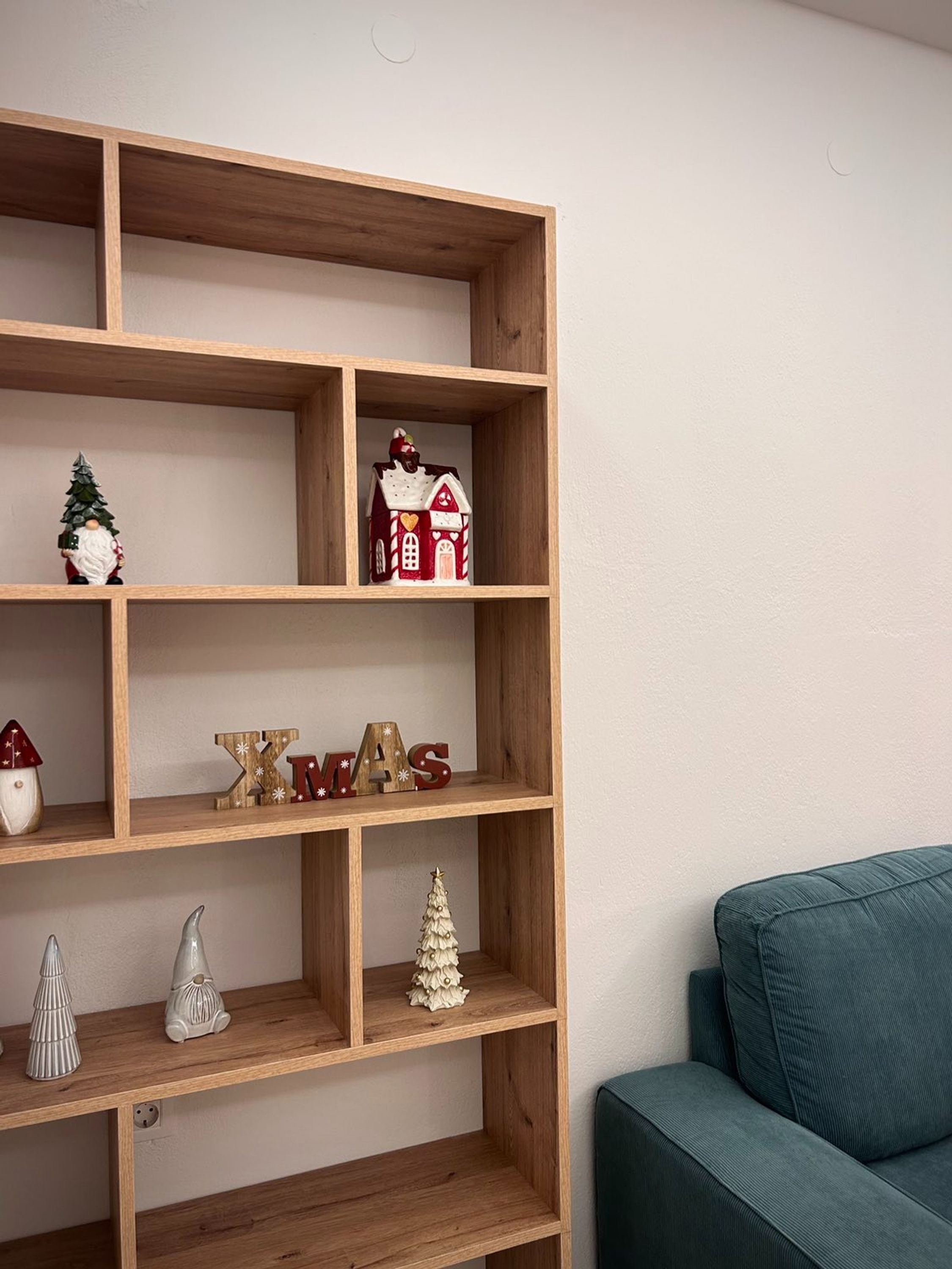 A wooden shelving unit with various Christmas decorations, including a Santa figurine, a Christmas tree, and a house-shaped ornament.