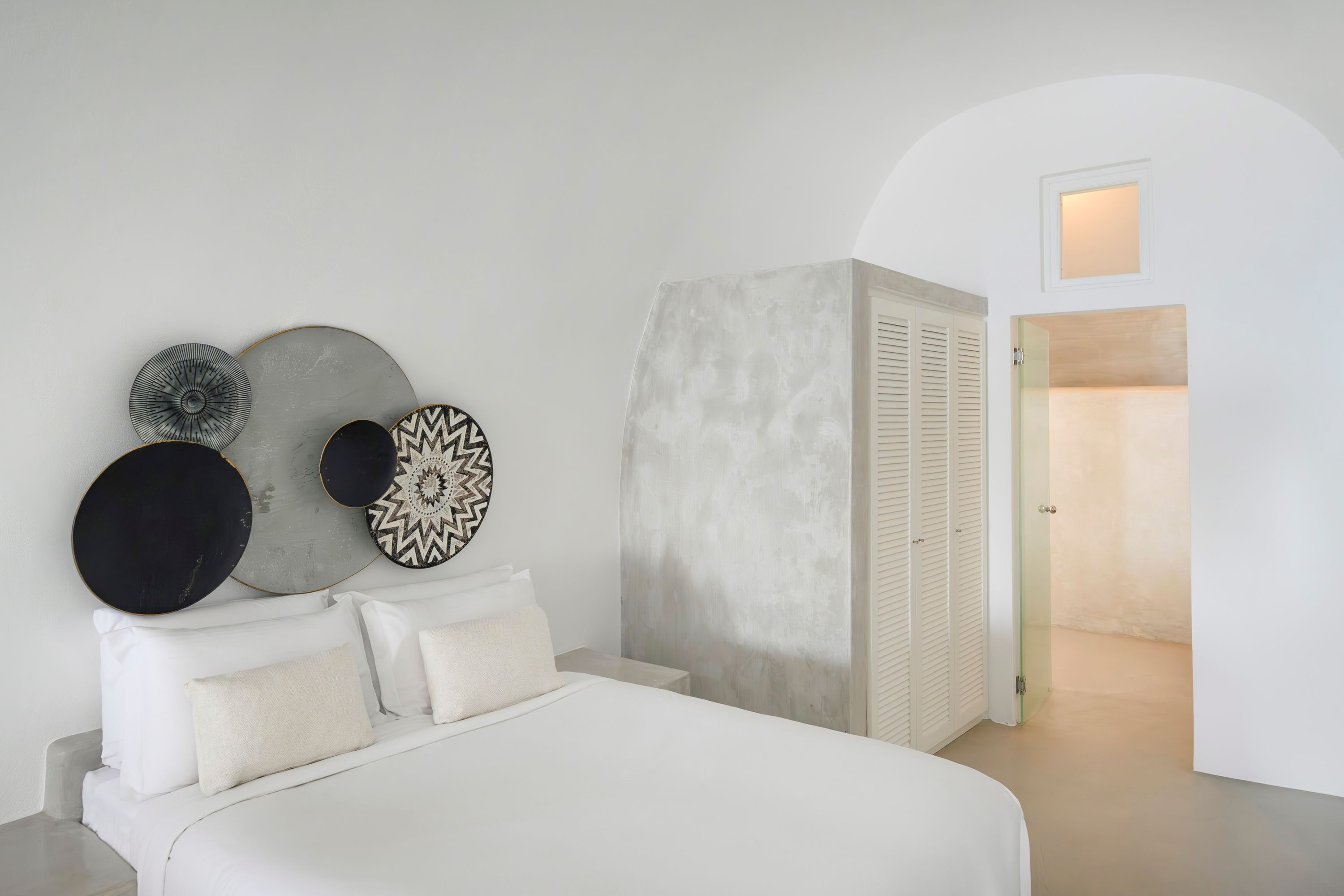 A bedroom with a bed, a wardrobe, and a wall with decorative plates.