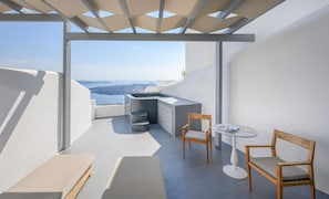 A modern balcony with a view of the sea, a small kitchen area, and seating. - Executive  Suite with Caldera View & Hot Tub (Santorini)