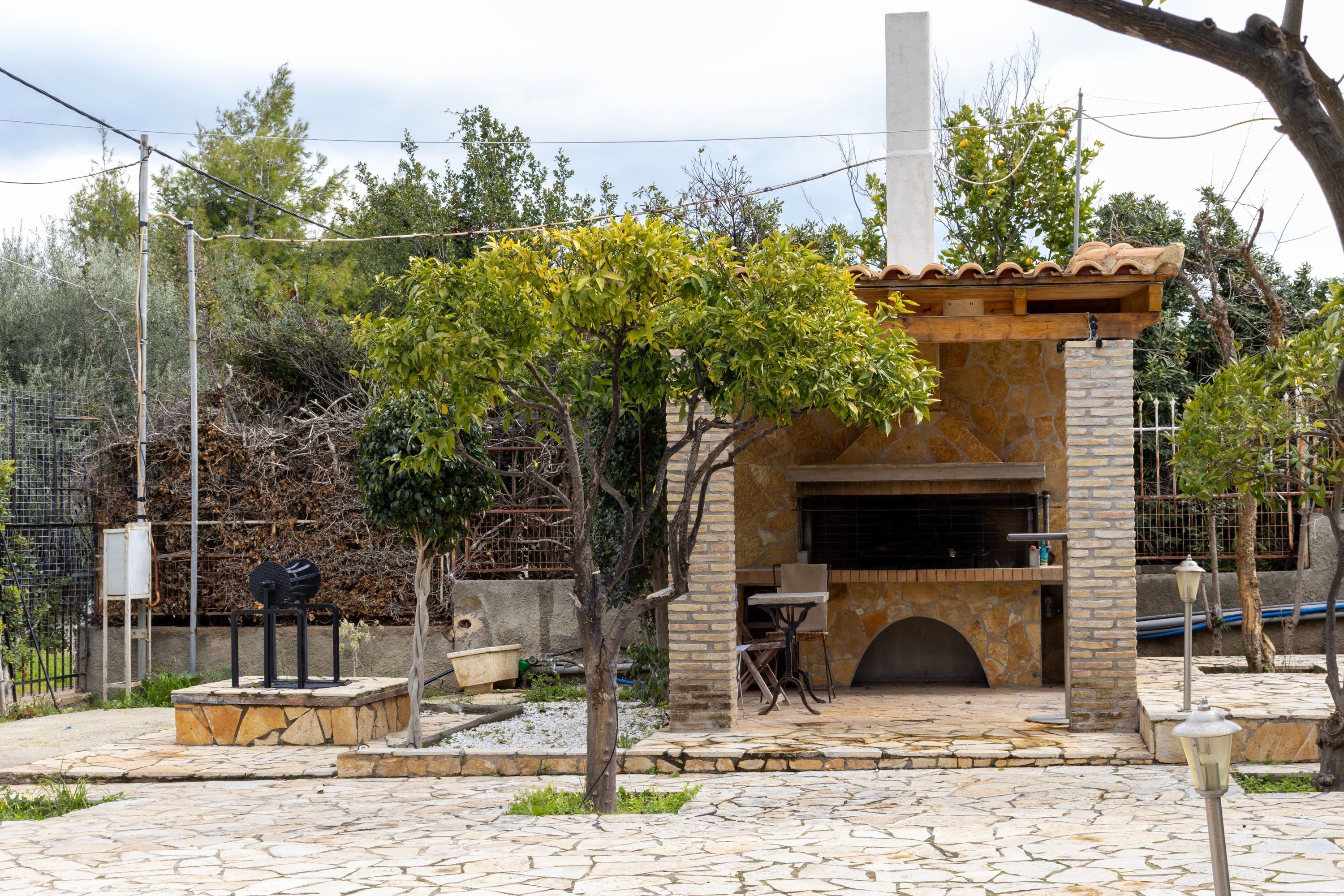 An outdoor patio with a stone fireplace, a small table, and a chair.