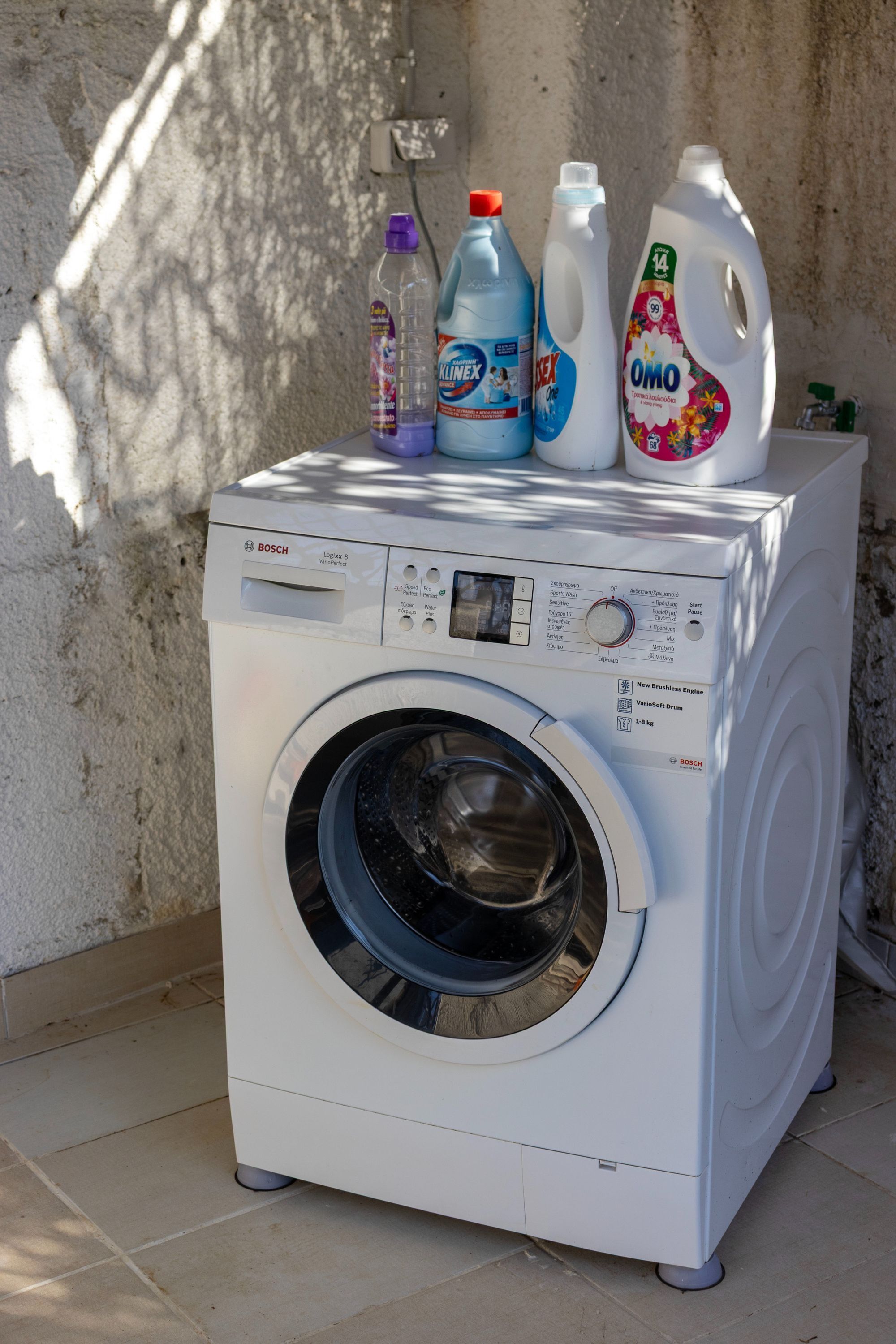 A Bosch washing machine with detergent bottles on top.
