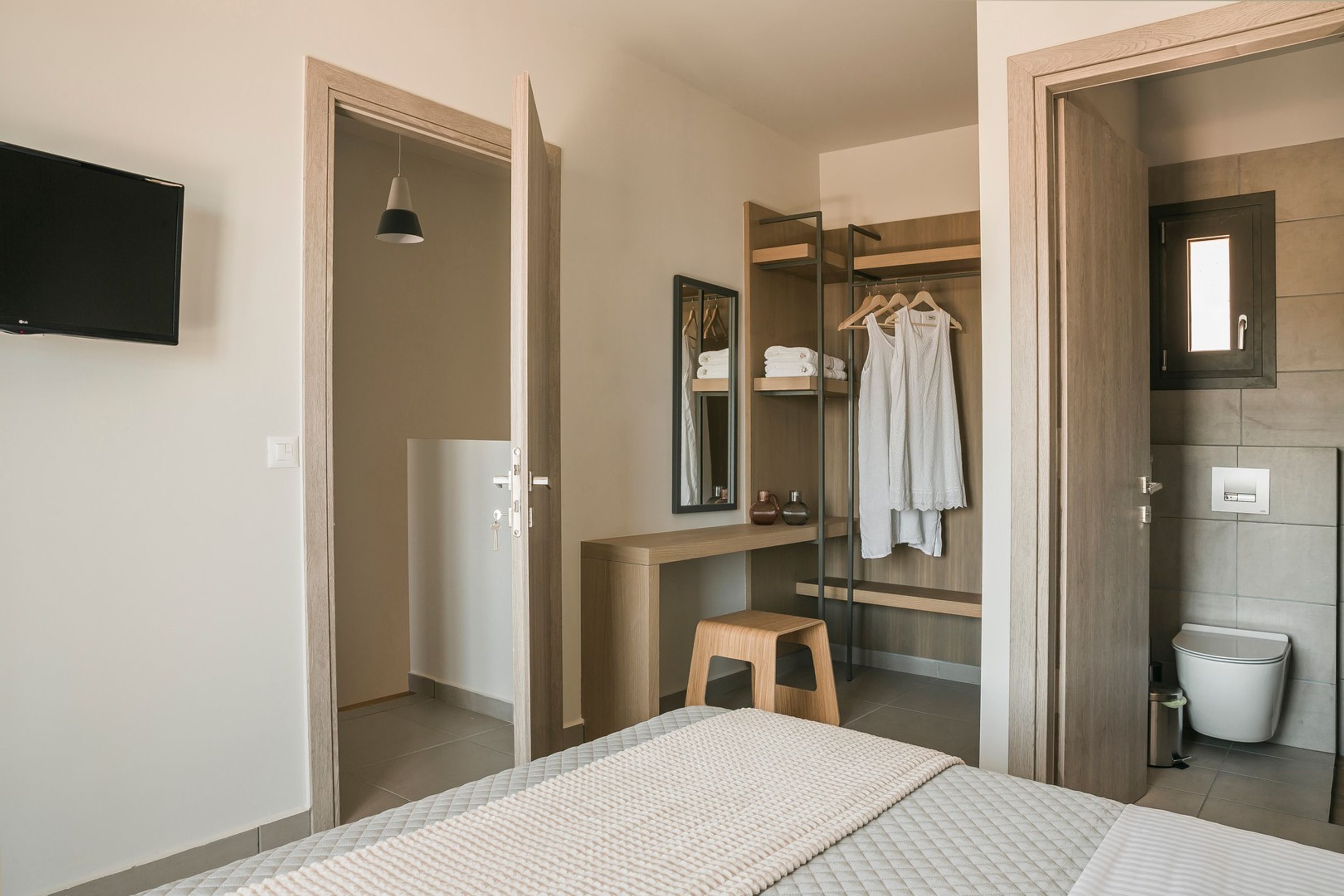 Une chambre moderne avec un lit, un bureau en bois, un miroir et une armoire.