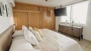 Une chambre à coucher avec un lit, une télévision et une armoire en bois.