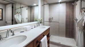 Ein modernes Badezimmer mit zwei Waschbecken, einem großen Spiegel und einer Duschkabine.