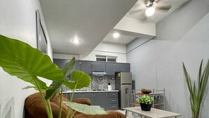 Una cocina moderna con armarios grises, una zona de comedor con mesa y sillas, y un ventilador de techo.