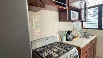 Una cocina con un refrigerador Winia, una estufa y armarios de madera.