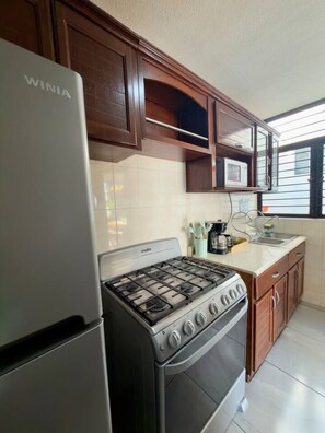 Una cocina con un refrigerador Winia, una estufa y armarios de madera.