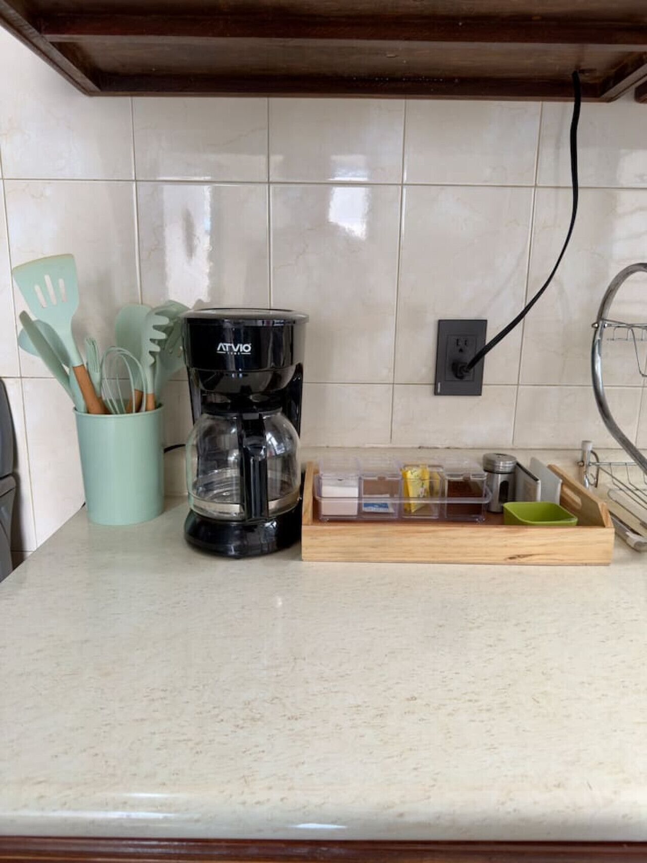 Une cuisine équipée d’une machine à café, d’ustensiles de cuisine et d’un plateau en bois contenant des récipients.