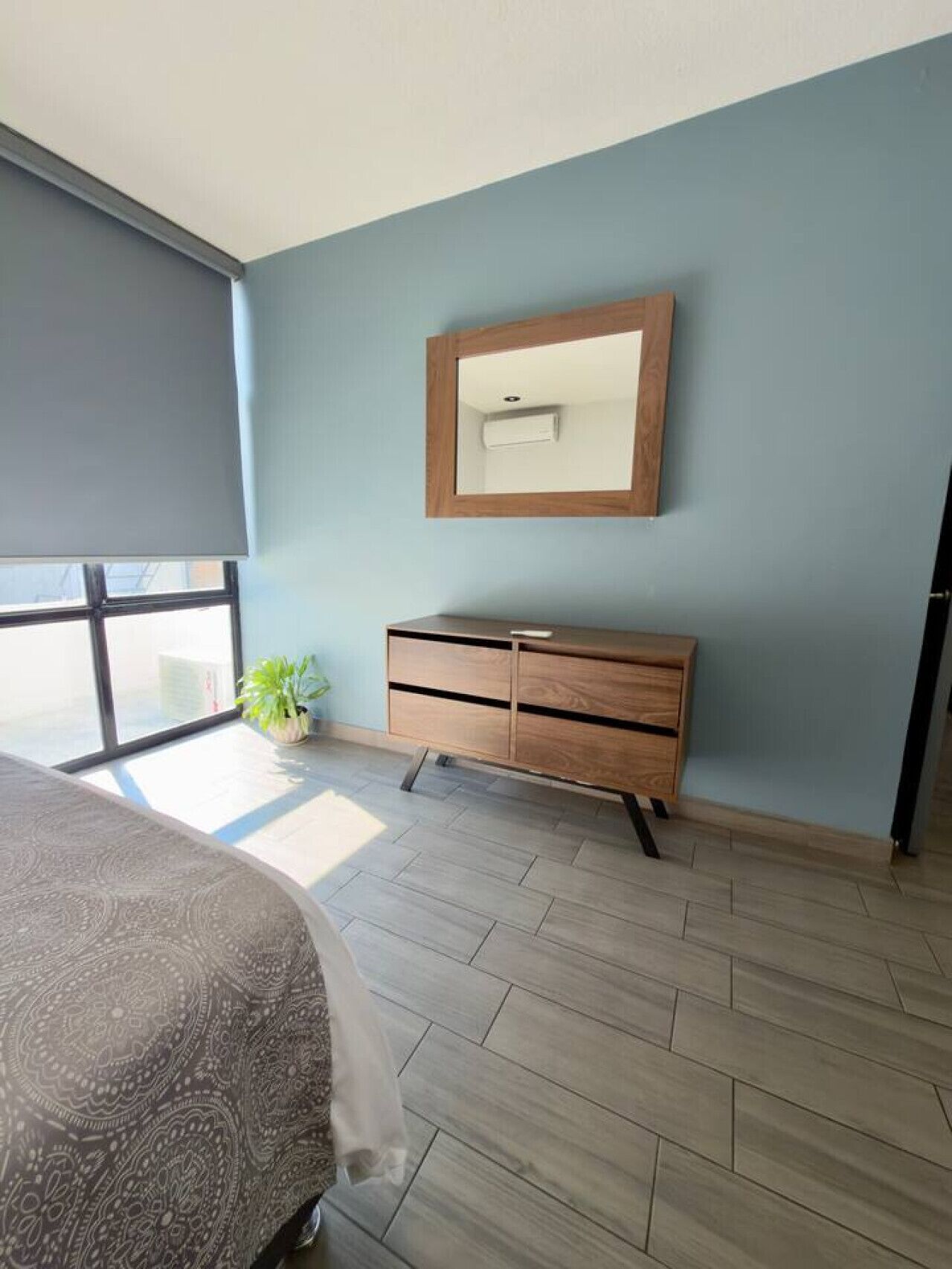 Un dormitorio con cama, cómoda, espejo y ventana con vistas.