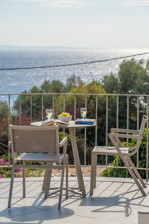 A terrace with two chairs, a table, and a book titled "The Wrong Side of the Road." - Villa Niki with swimming pool (Kefallonia)