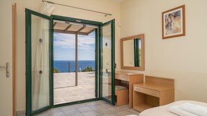 Una camera d'albergo con balcone, una scrivania in legno, un letto e un quadro appeso al muro.