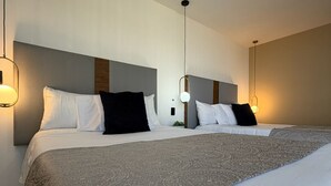 A hotel room with two beds, a large patterned bedspread, and pendant lighting. - AR Suites 4: La Calzada (Zamora de Hidalgo)