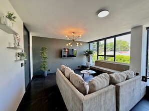 Un salon moderne avec un canapé, une table basse et un luminaire suspendu au plafond.