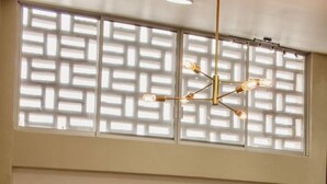 Un comedor con una mesa de madera, sillas amarillas, una lámpara colgante y un panel decorativo en la pared.