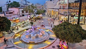 A public square with a central fountain, surrounded by cafes and shops. - City Center Apartment Project 3 by Cretan Houses (Iraklio)