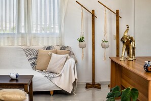 Ein Wohnzimmer mit einer Couch, einem Couchtisch, hängenden Pflanzen und einer dekorativen Elefantenstatue.